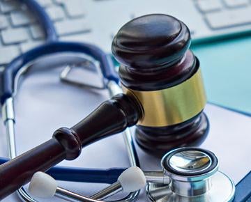 A gavel rests on top of a medical chart and stethoscope. 